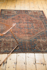 Vintage Southwest Persian rug corner, germinating plants, barber pole border, and visible pile wear.