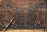 Vintage Southwest Persian rug's textured pile, displaying brick red and sapphire blue geometric motifs.