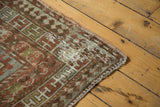 Running-T border and visible mending on distressed antique Caucasian rug corner.