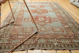 Distressed lower corner of antique Caucasian rug, highlighting rectilinear Running-T border and worn texture.