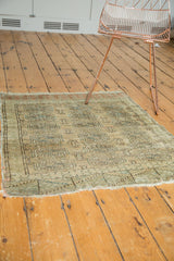 Distressed end and fringe detail of a vintage Turkmen rug with muted beige and green tones.