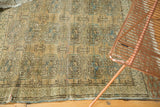 Distressed vintage Turkmen rug featuring muted beige, blue, and rust geometric guls, with a worn edge.