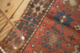Aged texture and geometric crab and starburst motifs on an antique Kazak rug.