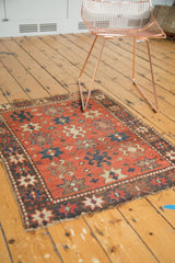 Visible edge wear and starburst motifs on the dark geometric border of an antique Kazak rug.