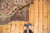 Folded vintage Distressed Malayer rug edge, with faded peach, blue, ivory geometric vinery.