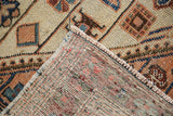 Distressed Malayer rug with folded corner showing geometric pile and hand-knotted weave.