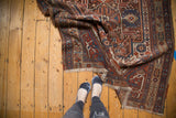 Fringed edge of antique Afshar rug, revealing detailed serrated patterns in madder red and blue.