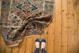 A folded corner of an antique Haji Jalili Tabriz rug showing intricate spandrels and scrolling vinery.