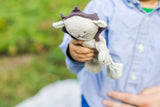 Gray organic cotton baby lion toy, with dark brown mane, held in a child's hand.