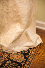 Vintage 60s wedding dress hem with cream lace detail over an antique patterned rug.