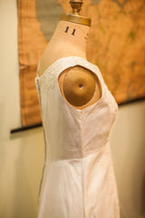 Vintage 60s wedding dress side view showing sleeveless design and delicate lace accents on ivory fabric