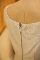Cream vintage 60s wedding dress, showing back zipper and floral lace accents.