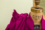 Fuchsia crepe dress showcasing gathered shoulder fabric and cuff with two pink buttons.