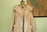 Soft ivory sheared fur coat detail, showing oversized collar and clear buttons.