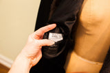 Hand revealing the white Dunhill Tailors brand label on black satin coat lining.