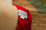 White Carolina Herrera Original Sample label on a bright red dress shoulder.