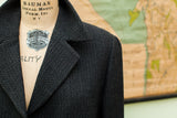 Close-up of vintage Giorgio Armani suit jacket's dark gray herringbone fabric.