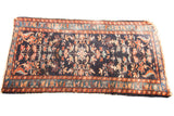 Vintage Persian Lilihan rug with deep indigo field, allover floral motifs in coral and teal.