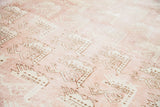 Repeating bird motifs on a light peach rose field of a vintage Oushak carpet.
