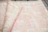 Vintage Oushak carpet corner with light peach rose field, visible hand-knotted weave, and deep rose side binding.