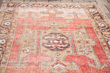 Distressed Oushak rug close-up: worn central medallion in red, saffron, charcoal, and beige.
