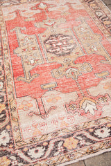 Distressed vintage Turkish Oushak rug close-up, showing red, charcoal, and saffron patterns.
