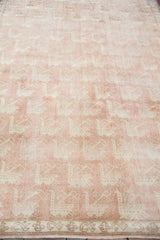 Close-up of the Oushak rug's repeating bird motif on a light peach field and border.