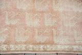 Peach rose field with repeating bird motifs and ornate border on a vintage Oushak rug.