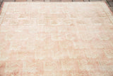 Repeating bird motifs on the soft peach rose field of a vintage Oushak carpet.