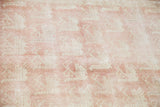 Repeating stylized bird motifs across the light peach rose field of the vintage Oushak.