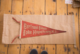 Vintage red felt pennant with off-white Gothic lettering, showing age and character.