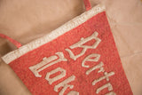 Vintage red felt flag detail, showing off-white gothic lettering and aged material.