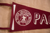 Close-up of vintage maroon felt flag's left edge, white hanging loop, and partial emblem.