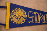 Close-up of yellow Simmons College seal and initial SIM on deep blue felt.