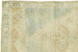 Faded blanched ivory, seafoam green, and beige patterns on a vintage Oushak rug.