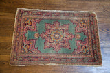 Mint green vintage Tabriz rug featuring a playful central medallion and distressed coral borders.