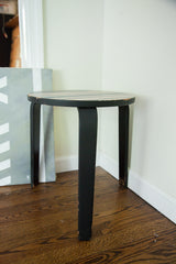 Alvar Aalto style occasional table with curved black legs and chipped paint.