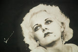 Vintage Jean Harlow art detail, showing expressive eyes and white graffiti mark.