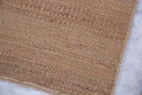 Handmade undyed jute rug texture with a natural woven edge.