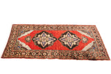 Vintage red Turkish rug runner featuring two central geometric medallions, 3'9
